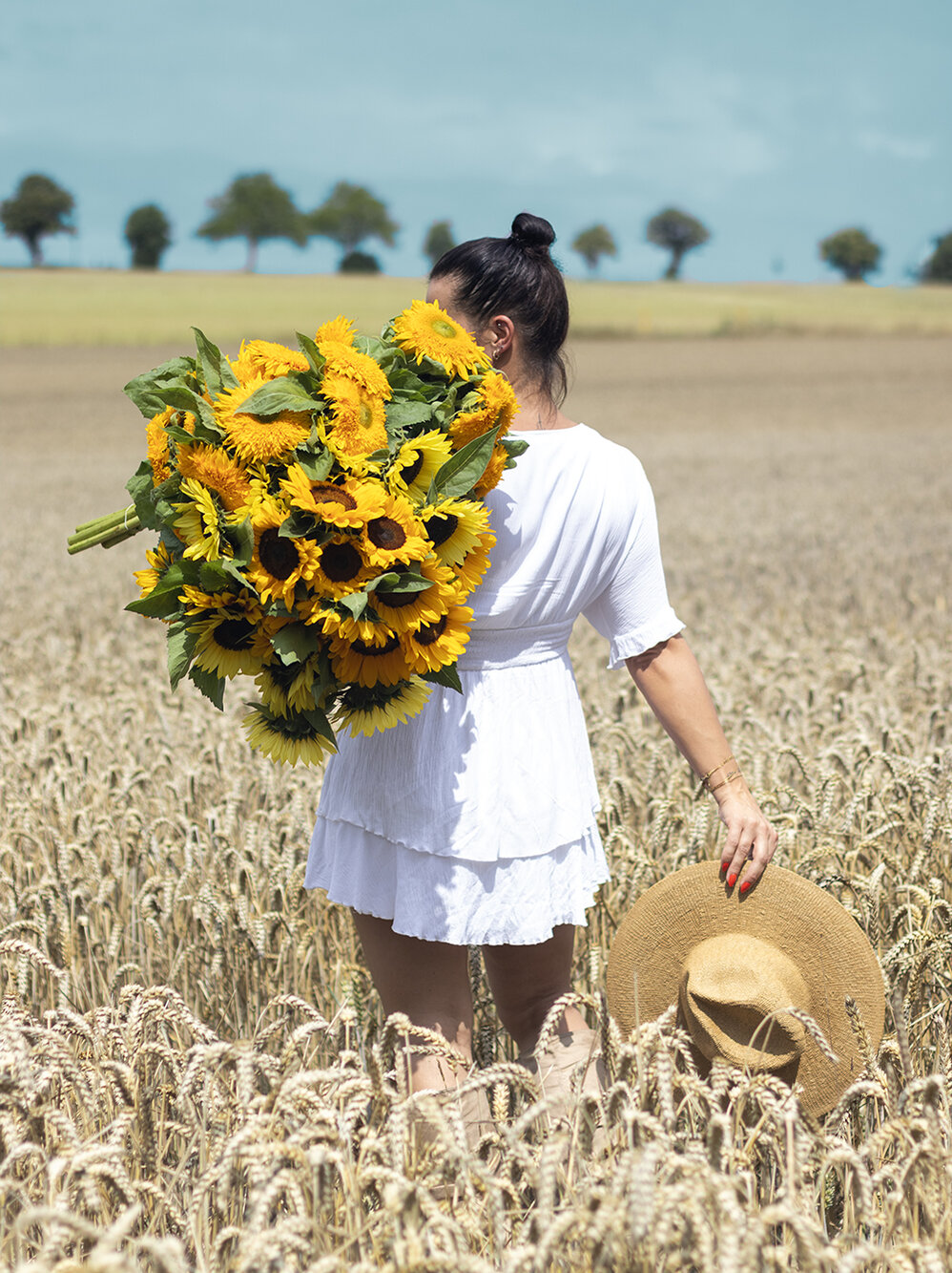 Blumen-Risse, Aktuelles, Aktion-Sonnenblumen, Frau-mit-Sonnenblumen-ueber-Schulter-laeuft-durch-Feld