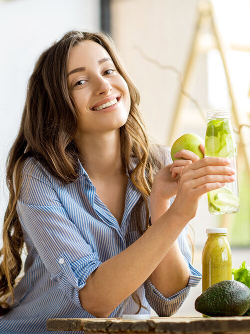 Blumen-Risse, Ratgeber, ganzjaehrige-Themen, Garten-und-Kuechenkraeuter, Frau-mit-frischen-Smoothies-sitzt-an-Kuechentisch