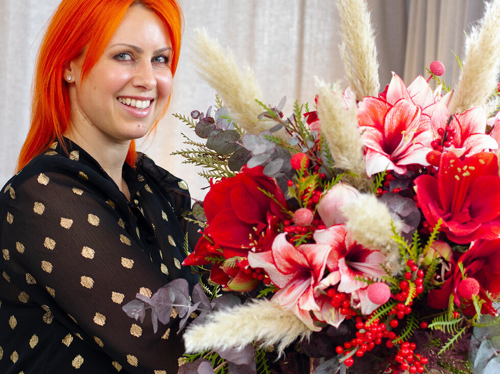 Frau-mit-orangenen-Haaren-haelt-festlichen-Amaryllisstrauß