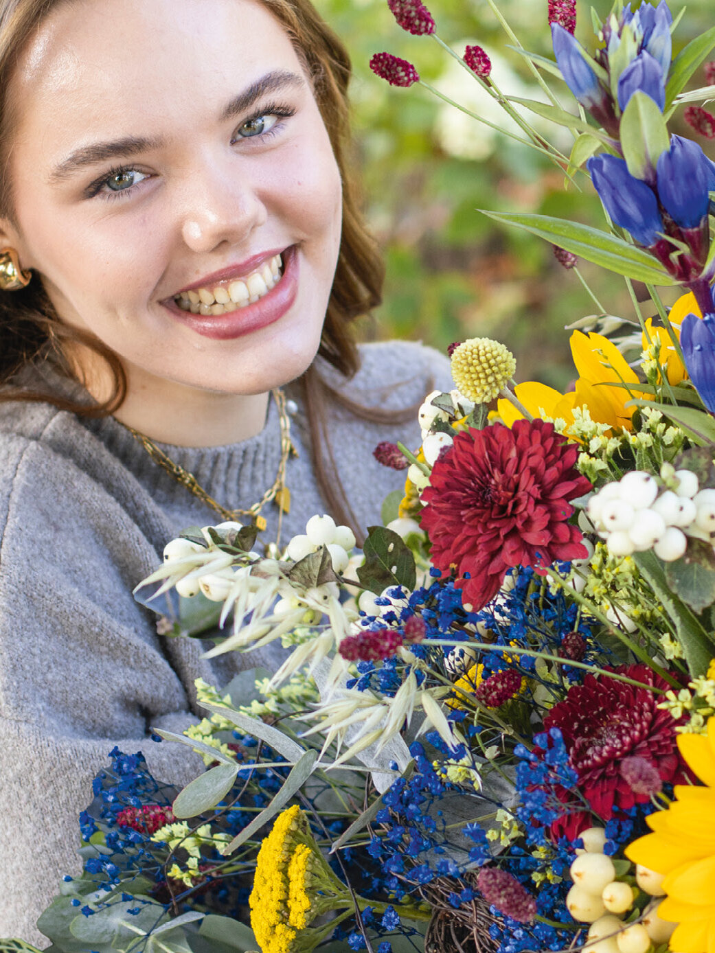 Blumen-Risse, Herbstfloristik, Herbst-Blues, Blue-meets-Autumn, Gelb, Rot, Blau, junge-Frau-hält-großen-spätsommerlichen-Blumenstrauss