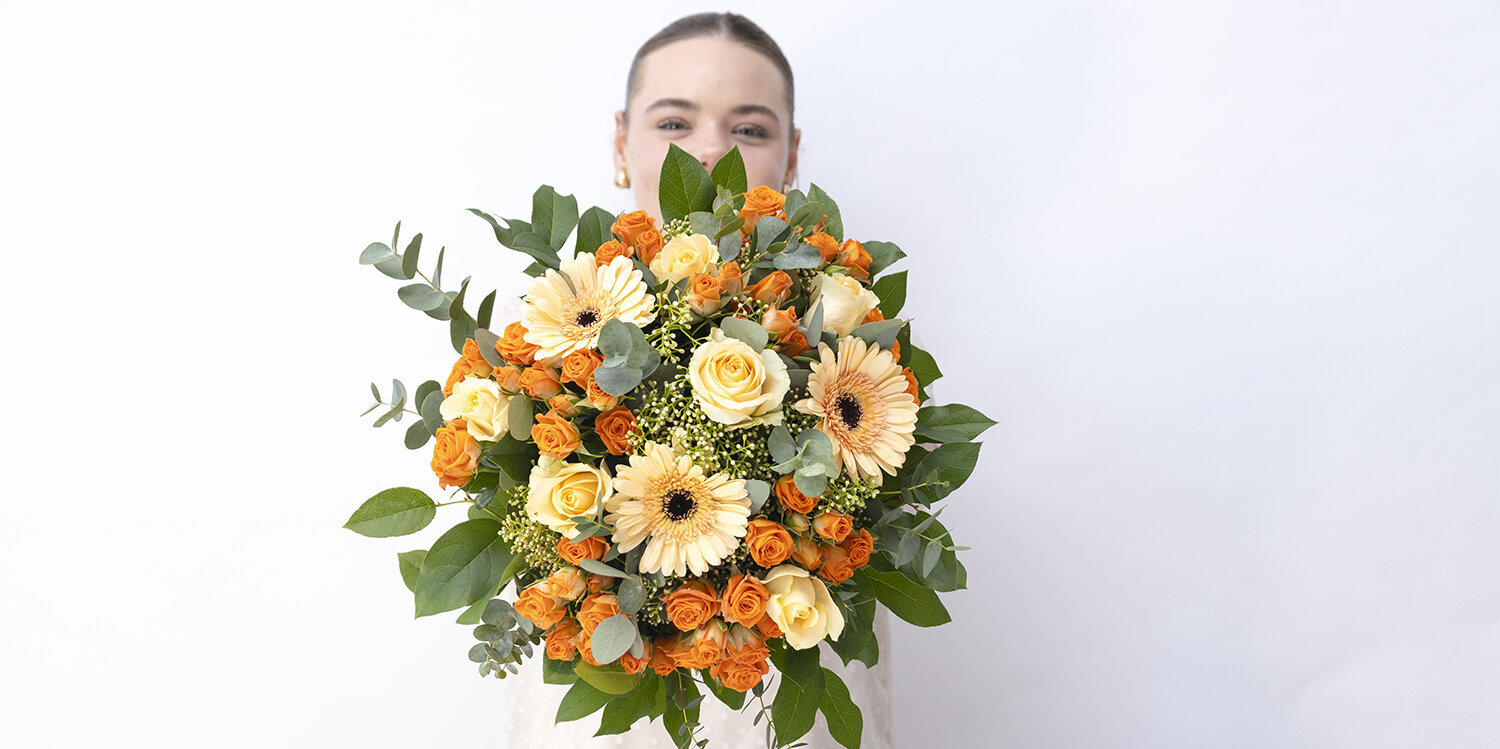 Blumen-Risse, Aktuelles, Aperol, Orange, Lachs, Frau-haelt-Blumenstrauss-frontal-in-Kamera