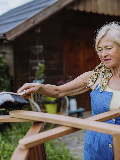 Blumen-Risse, Ratgeber, ganzjaehrige-Themen, Gartenmoebel-Pflege, Braun, Gruen, Grau, Frau-reingt-Gartenmoebel-mit-Handbesen