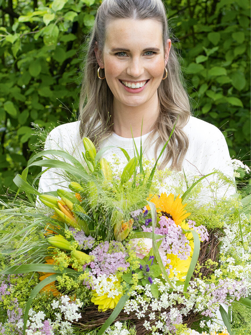 Blumen-Risse, Vor-Ort-News, Bluetenzauber-von-deutschen-Gaertnern, deutsche-Gaertnerware, Frau-mit-grossem-Sommerblumenstrauss-auf-Wiese