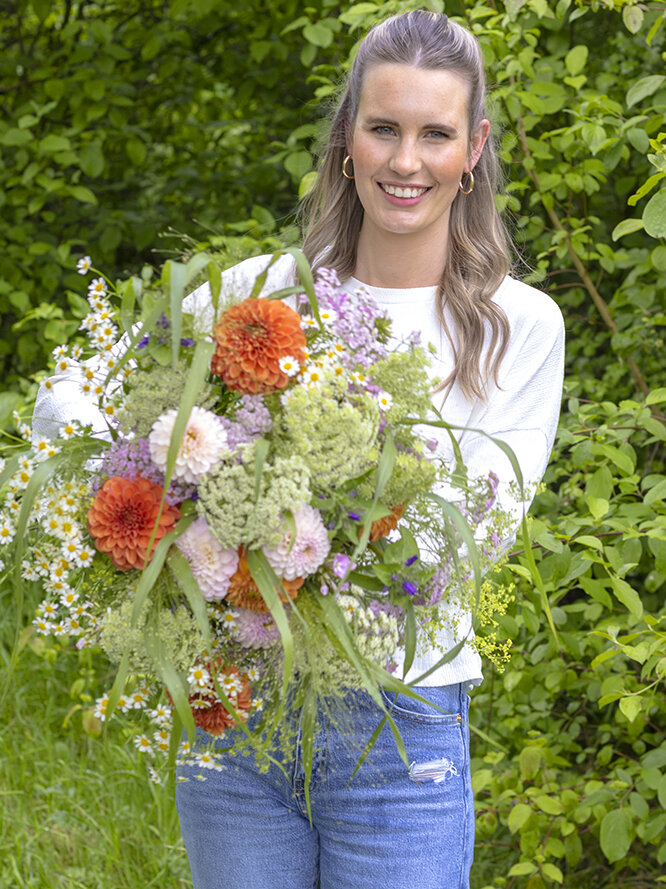 Blumen-Risse, Vor-Ort-News, Bluetenzauber-von-deutschen-Gaertnern, deutsche-Gaertnerware, Frau-mit-grossem-Sommerblumenstrauss-im-Gruenen