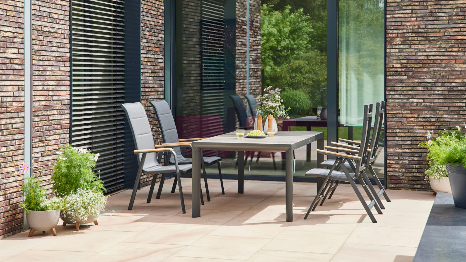 Blumen Risse, Markenwelt, Siena Garden, Sitzgruppe, Klappsessel, Schwarz, Esstisch, Schwarz, Holzplatte, Terrasse, Hauswand, Stein, Pflanzen, Grün